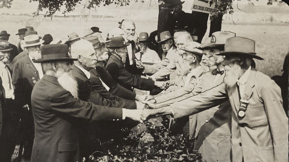 [Union and Confederate veterans shaking hands at reunion to commemorate the 50th anniversary of the battle of Gettysburg]